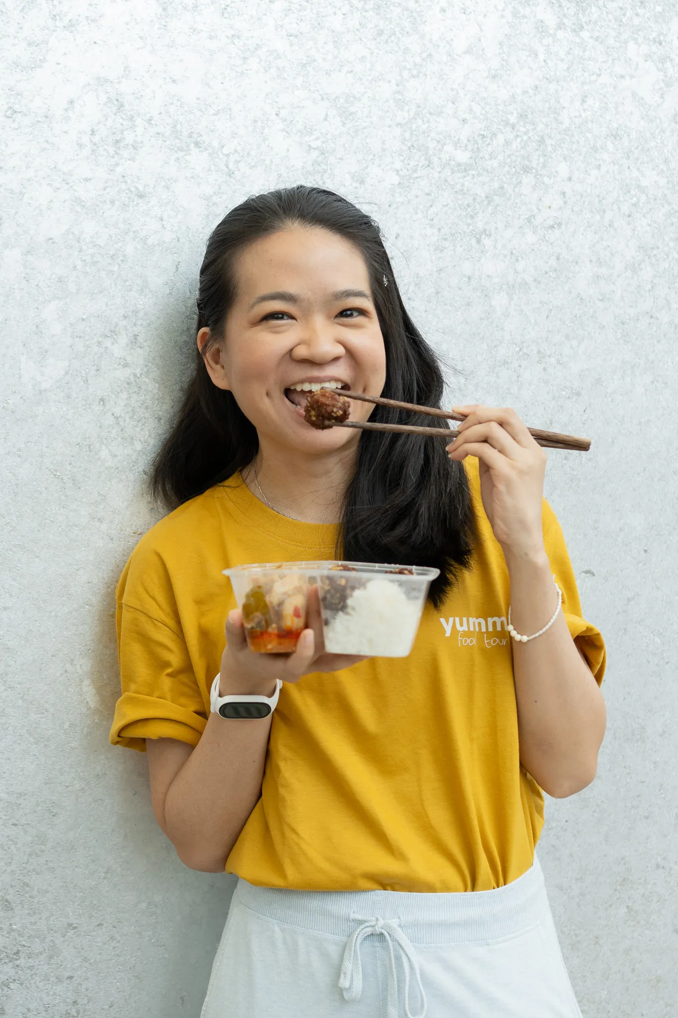 A Yummy team member eating a takeaway box of rice with chopsticks
